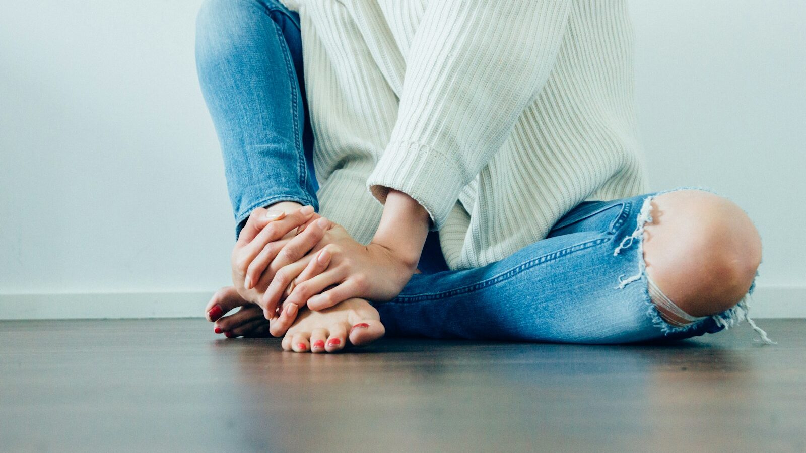 person wearing distressed blue denim jeans inside room